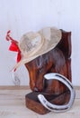 An old, wooden bookend of a horsehead with a straw hat and a horse shoe on wooden background.