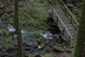 Wooden bridge over a rough flowing creek Royalty Free Stock Photo