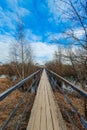 Old wooden bridge over the river in village. Narrow pedestrian crossing. Perspective. Spring nature outside the city