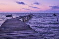 Old wooden bridge in the sea, early morning shot. Purple sky