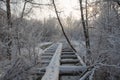 Old wooden broken footbridge covered with snow