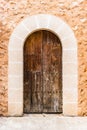 Rustic brown wood front door with stone arch and stone facade of mediterranen house Royalty Free Stock Photo