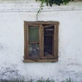 Old wooden brown window ruined by time on a light rustic wall of a house in the countryside in Europe Royalty Free Stock Photo