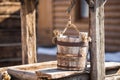 Old wooden bucket of water hanging over the well with a wooden building Royalty Free Stock Photo