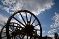 Old wooden buggy wheel spokes and axle silhouetted against the cloudy sky Royalty Free Stock Photo