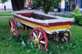 An old wooden cart painted with red and white paint on green grass Royalty Free Stock Photo