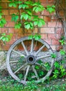 Old wooden cart wheel against wall Royalty Free Stock Photo