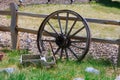 Old wooden cart wheel with small toy coach wagon farm, garden or front yard decoration in grass by fence countryside Royalty Free Stock Photo