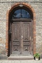 Old wooden carved double door, brick building entrance.