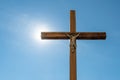 An old wooden Catholic cross against the background of the sun and clear blue sky. Religion and service to God as a path to Royalty Free Stock Photo