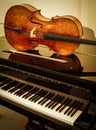 Old wooden Cello and bow on grand piano with cream background