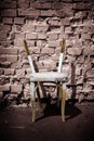 Old wooden chair without backrest against a brick wall background Royalty Free Stock Photo