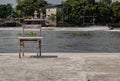 The old wooden chair is in front of the river, which is on the cement floor Royalty Free Stock Photo