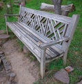 Old wooden chair in the park affected by time. Beautiful handmade ornament. Green grass background