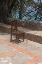 Old wooden chair, sitting on a cement patio, next to the ocean, abandoned. Nobody