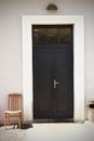 Old wooden chair in a yard near the black entrance door