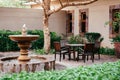 Old wooden chairs and table set in tropical backyard garden under tree with green shrubs