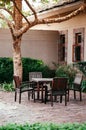 Old wooden chairs and table set in tropical backyard garden under tree with green shrubs Royalty Free Stock Photo