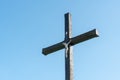 An old wooden Christian cross against a clear blue sky on a beautiful summer day. A statuette of Jesus in the center of the cross Royalty Free Stock Photo