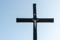 An old wooden Christian cross against a clear blue sky on a beautiful summer day. A statuette of Jesus in the center of the cross Royalty Free Stock Photo