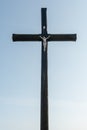 An old wooden Christian cross against a clear blue sky on a beautiful summer day. A statuette of Jesus in the center of the cross Royalty Free Stock Photo