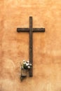 Old wooden christian cross on a wall decorated with flowers Royalty Free Stock Photo