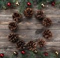 Old wooden Christmas background. Fir branches with baubles and gold stars. Cones in the shape of a circle. Gift in the middle Royalty Free Stock Photo