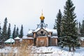 Old wooden church with golden dome and cross, houses in village in winter Royalty Free Stock Photo