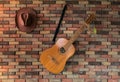 Old wooden classic guitar and cowboy hat hanging on brick wall Royalty Free Stock Photo