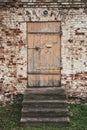 Old wooden closed door and steps in ancient brick building wall Royalty Free Stock Photo