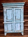 Old wooden closed window, shutters with peeling old blue paint, in an old wooden house made of logs, natural wood. Royalty Free Stock Photo