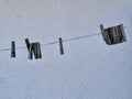 Old wooden clothes pins hanging on clothes line against white wall. Royalty Free Stock Photo