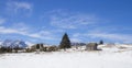 Old wooden cottage on a snowy meadow with mountain peaks in the background Royalty Free Stock Photo