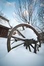 Old wooden cottage and wooden Romanian wheel covered by snow. Cold winter day at countryside. Traditional Carpathian mountains Royalty Free Stock Photo