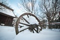 Old wooden cottage and wooden Romanian wheel covered by snow. Cold winter day at countryside. Traditional Carpathian mountains Royalty Free Stock Photo