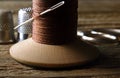 OLD WOODEN COTTON REEL WITH THICK BROWN COTTON THREAD, A NEEDLE AND THIMBLES AND A PAIR OF SCISSORS IN THE BACKGROUND Royalty Free Stock Photo