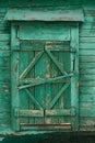 Old wooden country window with closed shutters painted green