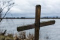 Old wooden cross on riverbank.