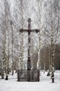 Old wooden cross in a small park of birches in winter