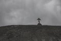 An old wooden cross stands on a high hill against the background of the sky.