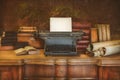 Desk with vintage typewriter holding an empty sheet of paper and ancient books and maps