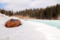 Old wooden destroyed flooded fishing boat lie in snow on shore of ice-covered frozen river in winter, snow in cold morning at Royalty Free Stock Photo