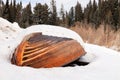 Old wooden destroyed flooded fishing boat lie in snow on shore of ice-covered frozen river in winter, snow in cold morning at Royalty Free Stock Photo