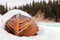 Old wooden destroyed flooded fishing boat lie in snow on shore of ice-covered frozen river in winter, snow in cold morning at Royalty Free Stock Photo