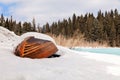 Old wooden destroyed flooded fishing boat lie in snow on shore of ice-covered frozen river in winter, snow in cold morning at Royalty Free Stock Photo