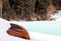 Old wooden destroyed flooded fishing boat lie in snow on shore of ice-covered frozen river in winter, snow in cold morning at Royalty Free Stock Photo