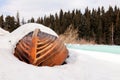 Old wooden destroyed flooded fishing boat lie in snow on shore of ice-covered frozen river in winter, snow in cold morning at Royalty Free Stock Photo