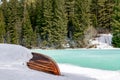 Old wooden destroyed flooded fishing boat lie in snow on shore of ice-covered frozen river in winter forest, snow in cold morning