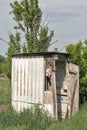 Old wooden dilapidated toilet in a village among the trees.