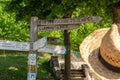 an old wooden directional sign next to a grassy field with trees Royalty Free Stock Photo